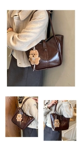 Detail of dark brown leather tote bag with plush dog charm for daily outfit look
