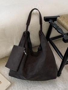 Minimalist large brown hobo tote bag with matching zipper pouch on a wooden chair