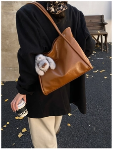 Detailansicht einer karamellbraunen Leder-Tote-Bag mit Plüschhasen-Anhänger am Modell