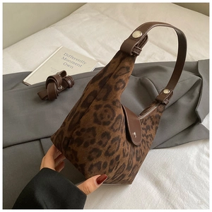 Dettaglio della borsa leopardata sottobraccio con cinturino in pelle marrone e fibbia