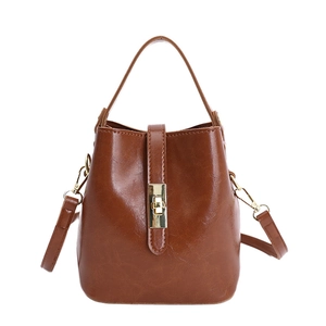 Brown leather bucket bag with gold metal lock and adjustable shoulder strap for women