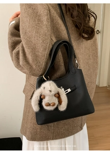 Detail of black pebbled leather bucket bag with silver twist lock and fluffy bunny charm