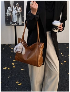 Nahaufnahme der braunen Shopper-Tasche aus Kunstleder mit grauem Plüsch-Hasenanhänger