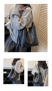 Detail of black faux leather bucket bag with gold rotary lock and adjustable shoulder strap