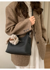 Détail du sac seau en cuir grainé noir avec fermoir tournant argenté et breloque lapin