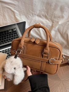 Brown leather crossbody square bag with white stitching and plush rabbit keychain charm