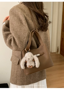 Deep brown pebble leather bucket bag with retro metal clasp and cute plush bunny charm