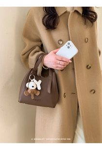 Detail of a brown lychee pattern leather bucket bag with cute cartoon animal charms