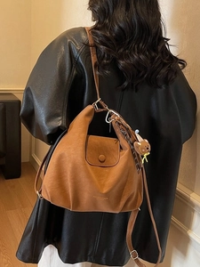 Vintage brown leather hobo bag with teddy charm on a black jacket model back view