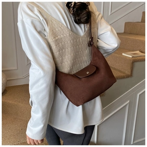 Dettaglio borsa hobo a mezzaluna in pelle scamosciata marrone scuro indossata da una modella