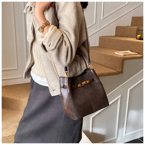 Detail of elegant two-tone suede bucket bag featuring polished gold metal twist lock