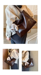 Detailansicht einer großen dunkelbraunen Lackleder-Tote-Bag mit Hasenanhänger am Riemen