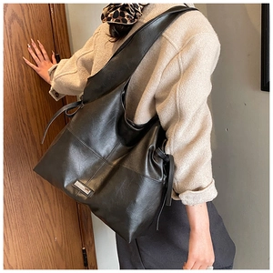 Close-up of black oil wax leather tote bag worn on shoulder for commuting style