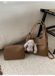 Détail de l'ensemble sac seau en cuir marron motif litchi avec breloque lapin en peluche