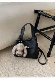 Détail d'un sac seau noir grainé avec fermoir rotatif argenté et charm lapin en peluche