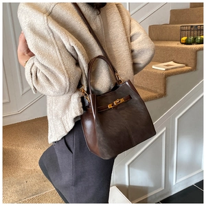Detail of dark brown leather bucket bag with gold clasp shown on stairs