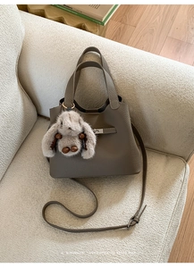 Détail du sac seau en cuir gris avec fermoir barre en métal et charm lapin en peluche