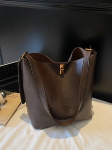 Retro dark brown leather bucket bag with gold hardware on a minimalist office desk