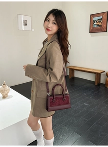 Chic burgundy leather handbag styled with elegant attire in a minimalist indoor setting