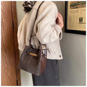 Detail view of retro brown suede handbag with gold buckle and adjustable shoulder strap