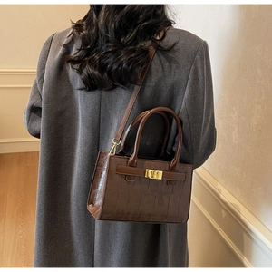 Detailed view of dark brown faux crocodile leather crossbody bag with golden twist lock