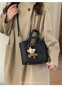 Black pebbled leather bucket bag with bear charm shown in a lifestyle setting