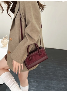 Detailed close-up of retro dark red leather and suede tote bag with sphere handle decor