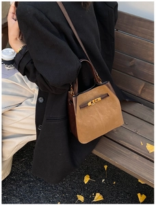 Detail of suede and brown leather bucket bag with gold metal twist lock mechanism
