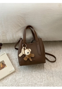 Top-down view of brown lychee texture leather bucket bag with a cute monkey charm decoration