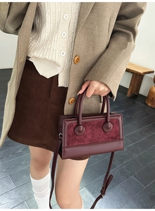 Detail of burgundy faux suede and smooth leather bag with spherical handle accents