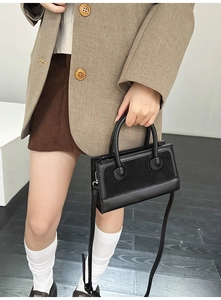 Detail of vintage black crossbody bag with matte leather stitching and decorative buckles
