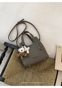 Detail of taupe leather bucket bag featuring lychee texture and cute puppy charm