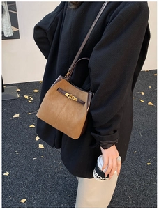 Detail of suede bucket bag with gold lock shown in a stylish lifestyle street setting