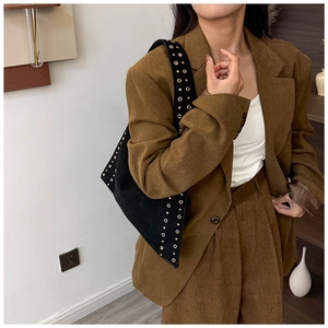 Detail of black vintage rivet shoulder bag with metal grommets styled on corduroy blazer