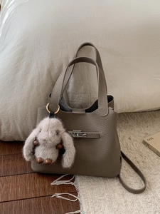 Sac seau minimaliste en cuir taupe avec fermoir métallique et breloque lapin en peluche