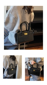 Detail of black crocodile texture handbag featuring golden twist lock and adjustable strap