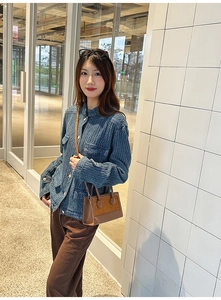 Detail of vintage textured blue jacket with gold buttons and two-tone brown leather handbag