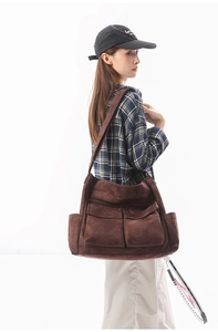Detailed side view of large retro dark brown canvas shoulder bag on female model