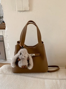 Sac seau minimaliste en cuir marron avec boucle argentée et breloque lapin en peluche