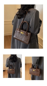 Detail of dark brown crocodile embossed crossbody bag with gold-tone twist lock closure