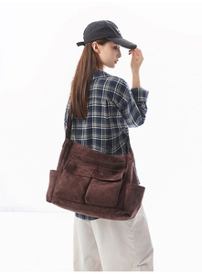 Detail view of large dark brown canvas messenger bag with functional utility pockets