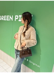 Detail of coffee brown crossbody bag paired with a beige quilted winter fleece jacket