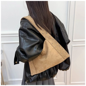 Close-up of brown suede shoulder bag with vintage metal rivets and eyelet details