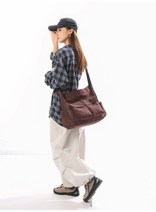 Detail of a brown canvas shoulder bag with dual front pockets and large storage space