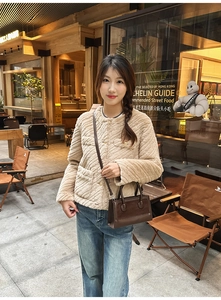 Detail of a dark brown leather handbag styled with a beige faux fur jacket and jeans
