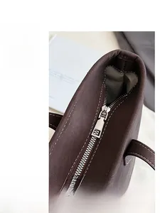 Détail de la fermeture éclair et des surpiqûres blanches sur un sac cabas en cuir marron