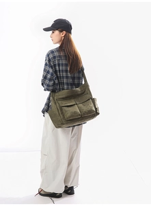 Side view of olive green canvas messenger bag featuring functional cargo style multi-pockets