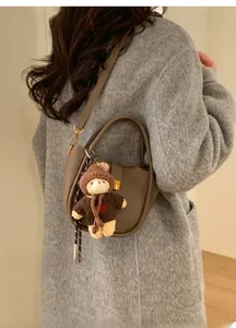 Détail du sac seau en cuir marron foncé avec charm d'ours et fermoir en métal doré