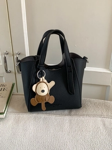 Chic black pebbled leather bucket bag with wide handles and a cute monkey charm