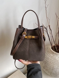 Brown suede bucket bag with gold C-clasp, stylish handbag shown in a lifestyle setting